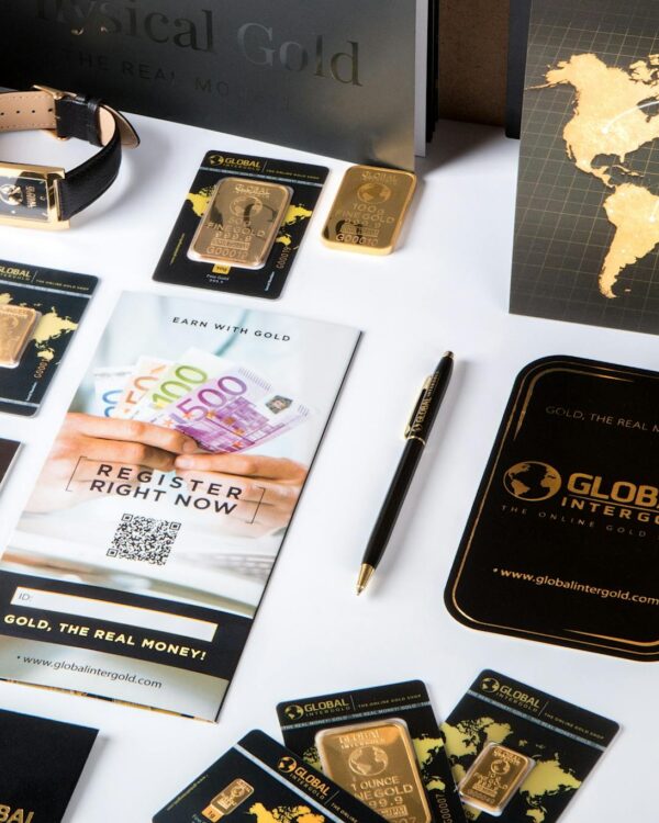 Flat lay of promotional materials for gold investment, featuring brochures, cards, and gold bars.