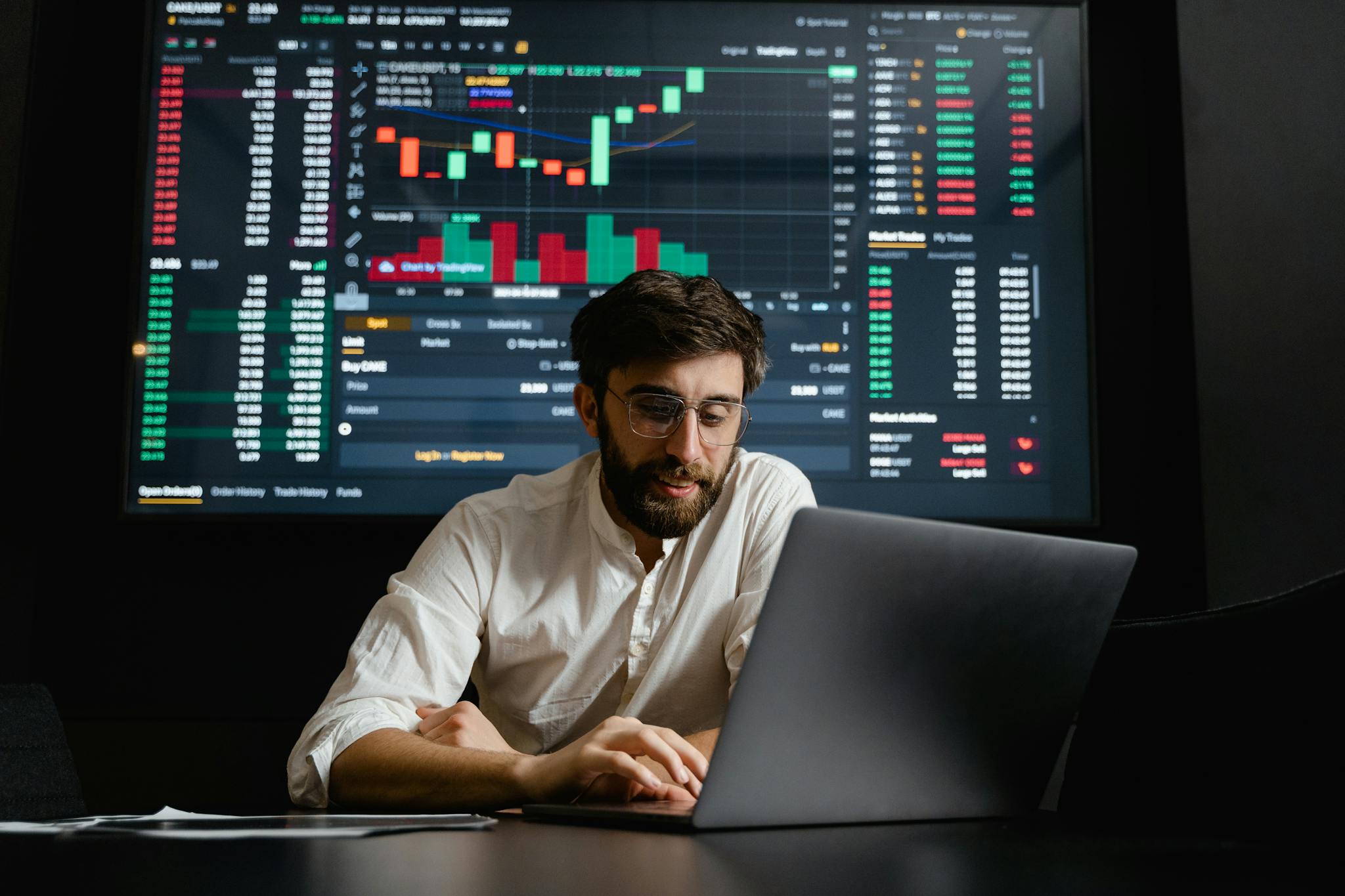 Contact Male analyst studies cryptocurrency trends at a workstation with multiple displays showing market data.