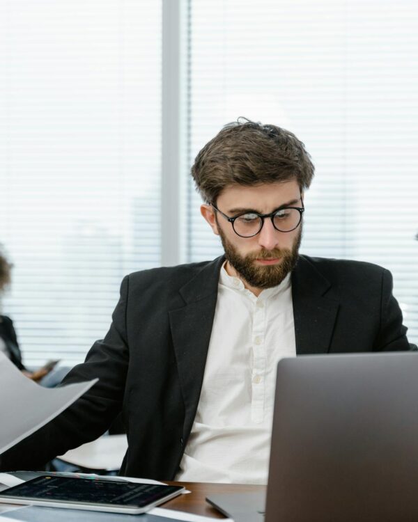 Two business professionals analyzing data on a laptop in a modern office setting, focusing on strategy.