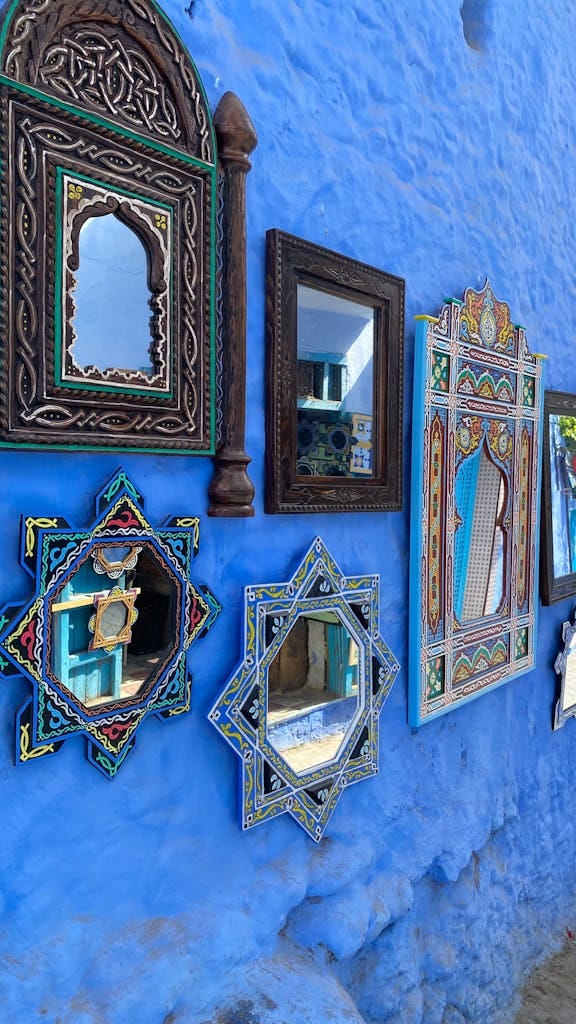 Best Home Décor Accessories to Elevate Your Space in 2026 Colorful decorative mirrors against a traditional blue wall in Chefchaouen, Morocco.