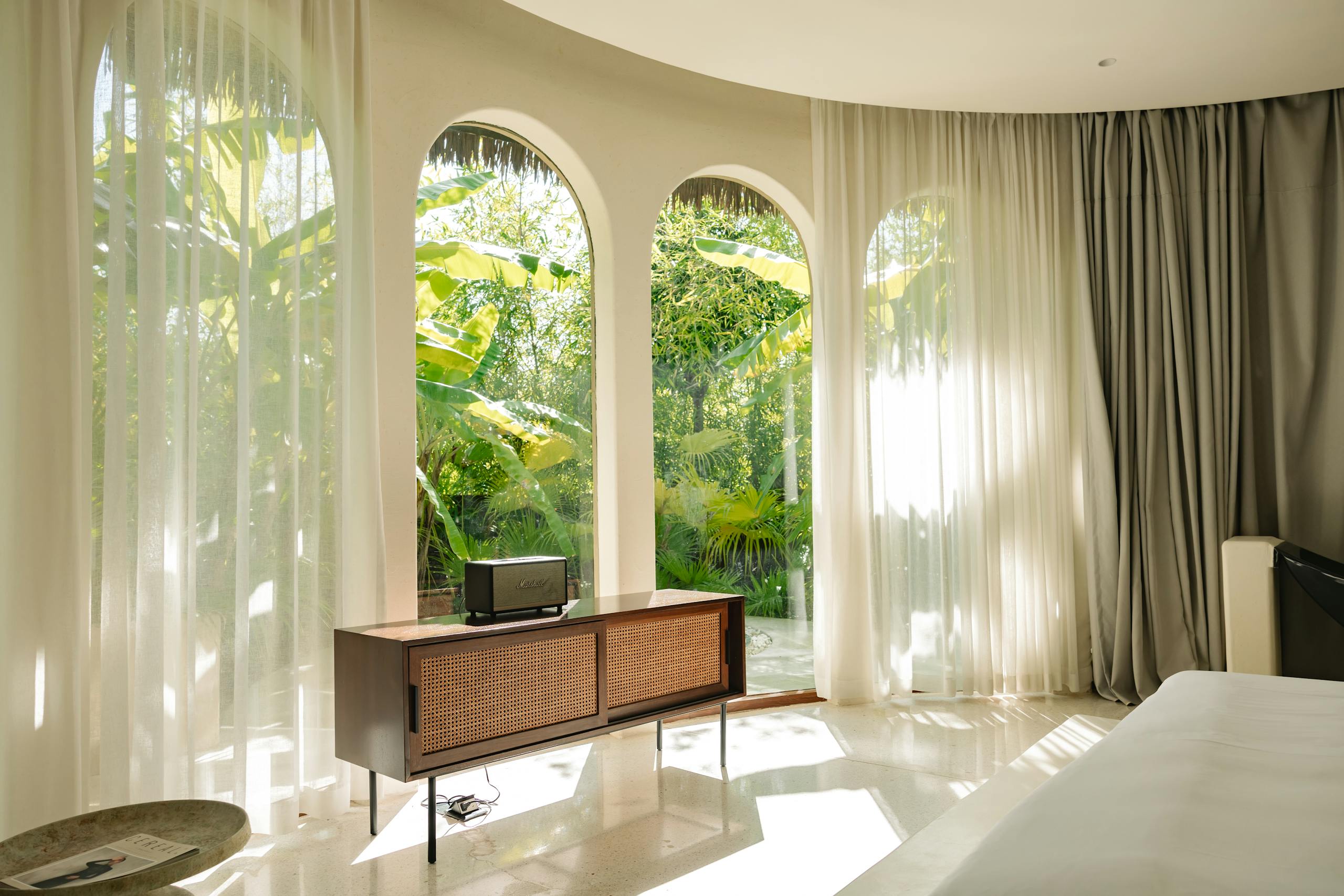 Luxurious room with garden view, featuring sunlight and minimalist decor.